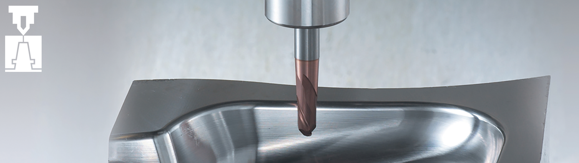 A metal cutting tool is positioned above a smooth, curved metal surface, likely for milling or machining. The T-shaped white logo is visible in the top left corner against a grey background.