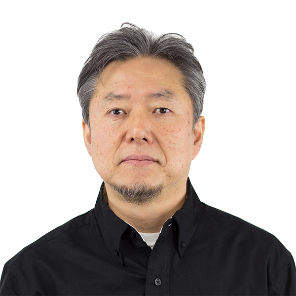 A middle-aged man with short gray hair, a trimmed goatee, and a neutral expression is facing the camera. He is wearing a black button-up shirt over a light-colored undershirt. The background is plain white.
