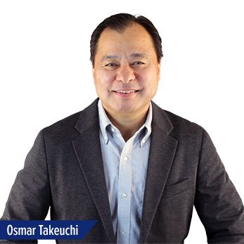 Osmar Takeuchi Press Release Profile_web A man with short dark hair is smiling at the camera. He is wearing a light blue button-up shirt and a dark blazer. The name Osmar Takeuchi appears in white text on a blue label in the lower left corner.