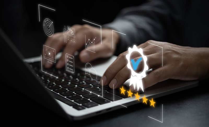 News-Media-Content-Library_800x486 Close-up of hands typing on a laptop keyboard with digital icons, including a check-marked badge and five stars, overlaid to represent quality, certification, and data analysis.