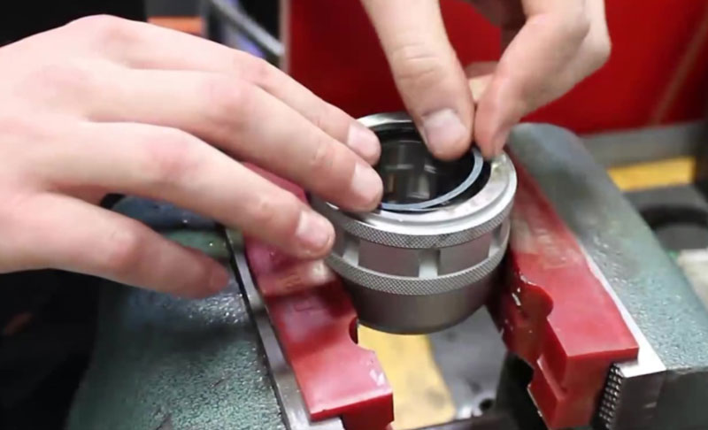 A person is adjusting the components of a Milling Chuck, held in place by a red and green vise.