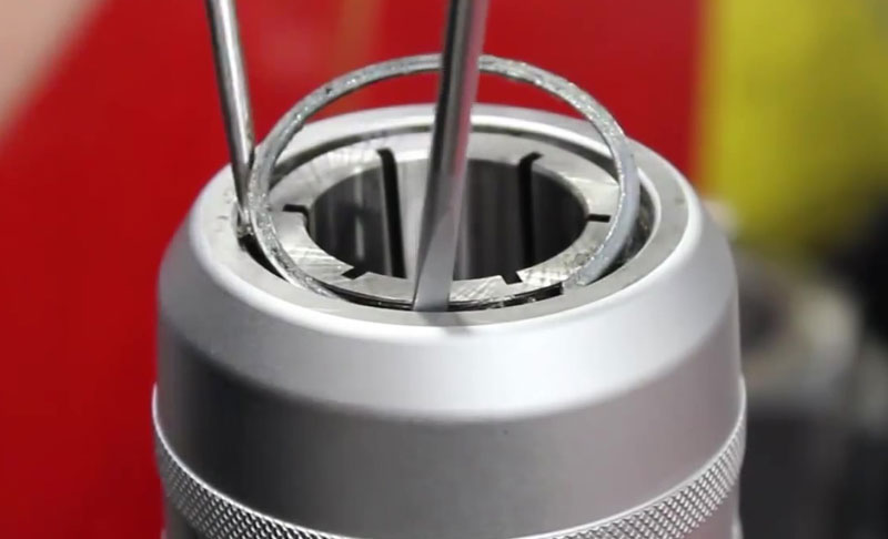 Close-up view of a Milling Chuck with a circular retaining ring being adjusted using a pair of precision pliers.
