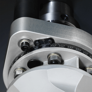 Close-up of a right angle head with bolts and a circular vernier scale marked in degrees from 0 to 360, used for precise angular adjustments.