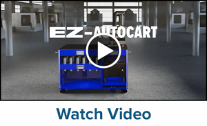 A blue automated cart with storage compartments is positioned inside a job shop. The text EZ-AUTOCART appears at the top center, with a play button icon overlayed. Below is the text Watch Video.