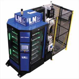 The EZ-TEND modular CNC machine tending platform with a touchscreen control panel, safety lights, and a protective metal fence, used for automated manufacturing or machining processes.