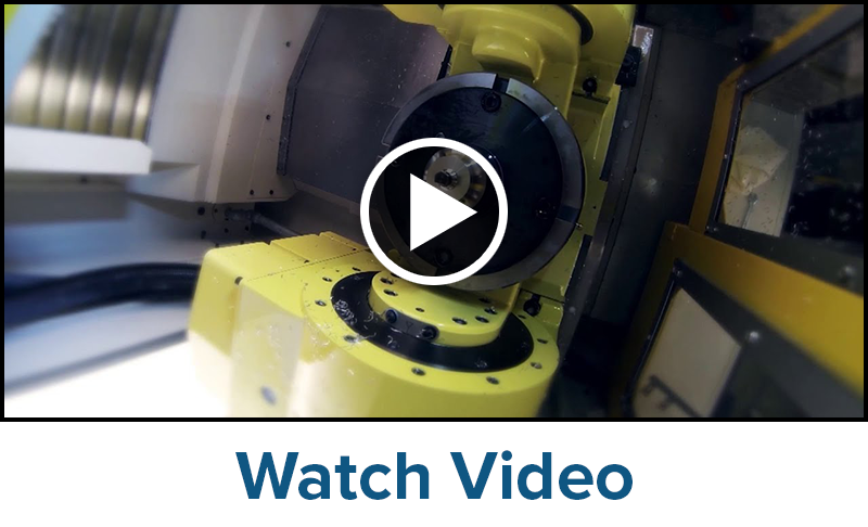 Close-up view of a yellow Nikken Rotary Table inside a manufacturing facility, with a play button in the center indicating a video, and the text Watch Video below the image.