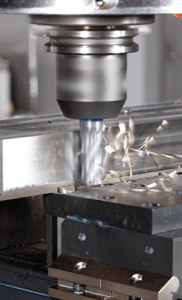 A CNC milling machine, equipped with a secure clamping system, cuts a metal workpiece as metal shavings fly off from the rotating cutting tool shaping the material.