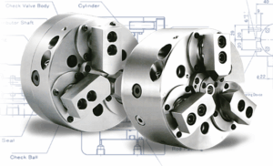Two large, round Hydraulic Power Chucks with multiple holes, bolts, and protruding components are shown in front of a faint technical blueprint background.