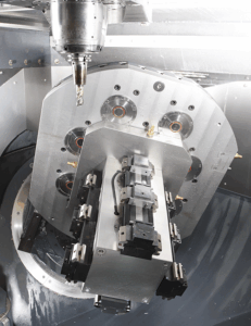 A close-up view of a CNC machine tool with a rotating spindle, clamping system, and multiple tool holders, highlighting the mechanical components and precision engineering of the equipment.